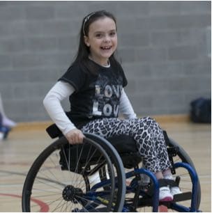 Photograph of a smiling girl in a wheelchair doing sport